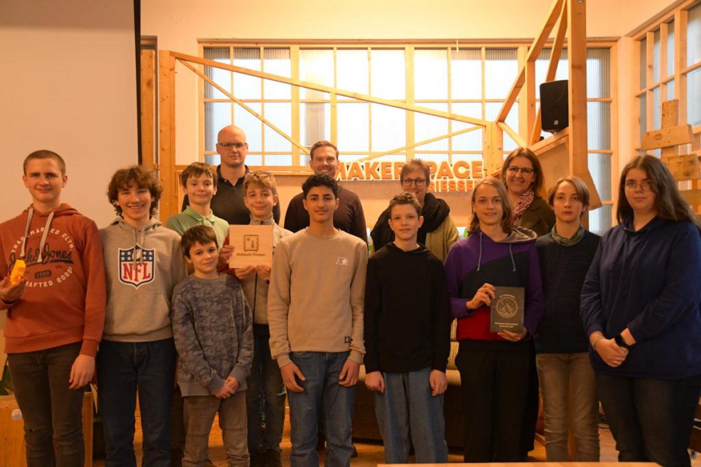 Gründungs-AG Gießen, erster Durchlauf: Initiatoren, Lehrkräfte und Teilnehmende freuen sich über die ersten Erfolge der Lösungsfinder*innen-AG (letzte Reihe von links nach rechts): Florian Bach (Ricarda-Huch-Schule), Nils Seipel (flux – werk gGmbH), Beate Brunkau (Liebigschule), Antje Bienert (TIG GmbH); Es fehlen Hilde Hammermann (Landgraf-Ludwigs-Gymnasium) und Robert Dörre (Ostschule). Vorne im Bild: An der AG teilnehmende Schülerinnen und Schüler (Foto: privat).